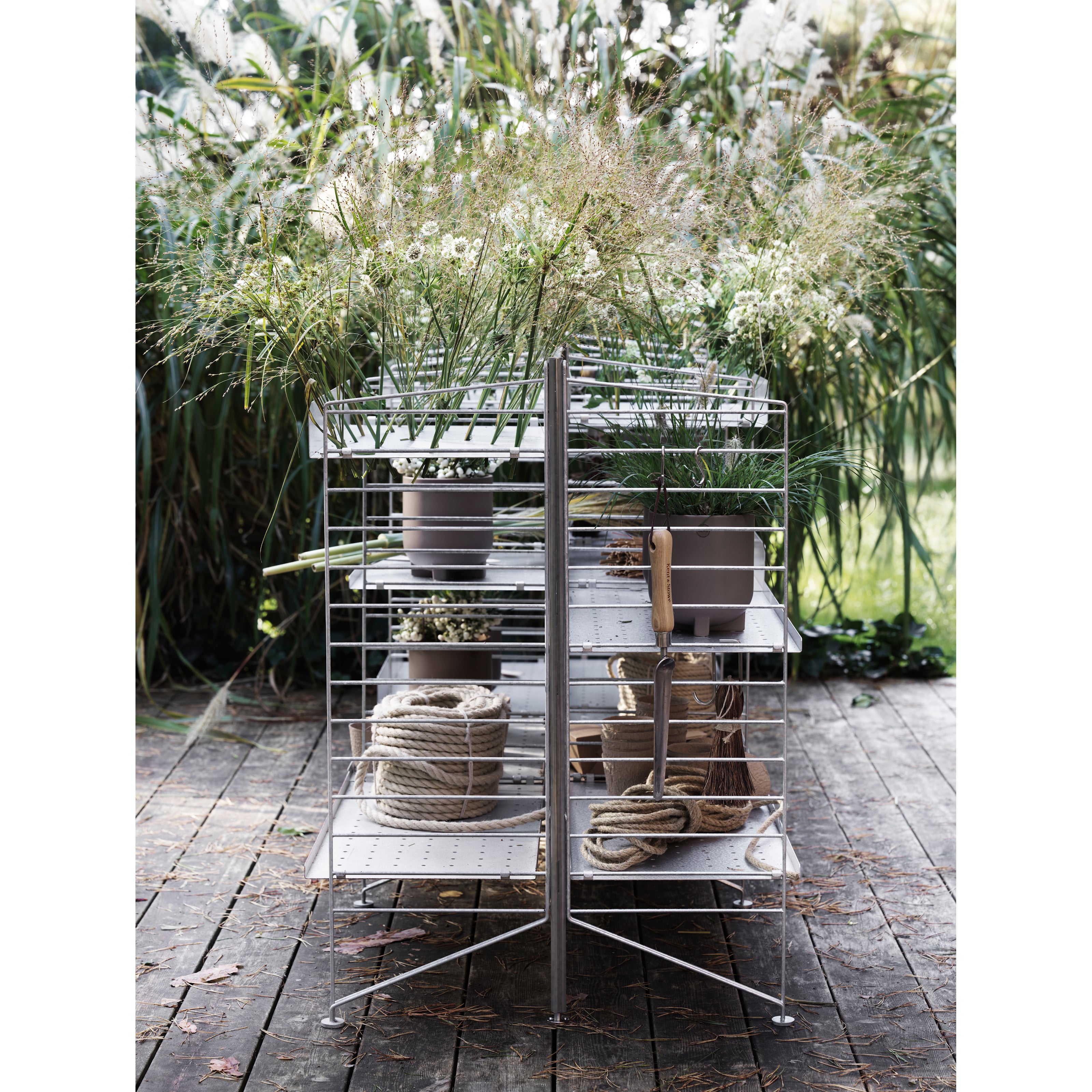 Free standing galvanized shelf intended for outdoor use. This smaller one section combination is optimized with shelves on either side of the shelf. A mix of galvanized metal shelves with high and low edge give the shelf character and further storage possibilities. The galvanized material changes over time and leaves you with a beautiful patina.